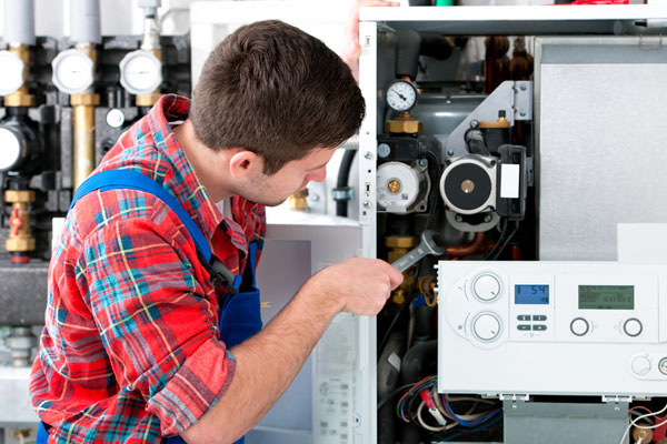 HVAC technician inspecting and repairing boiler controls in Syracuse