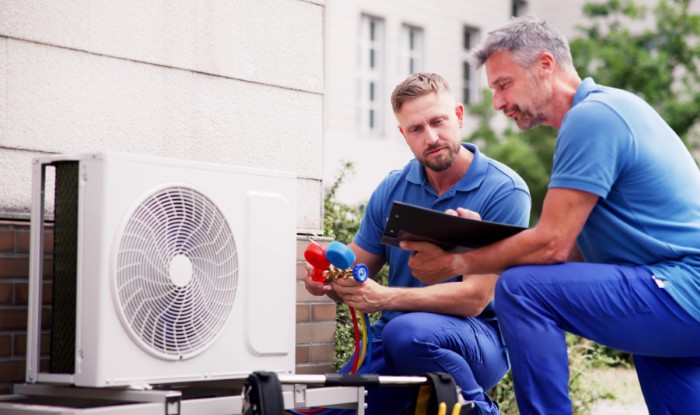 HVAC technicians installing an outdoor air conditioning unit in Syracuse