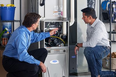 65df8c11f3e4c468cbd351a5_furnace repair vs replacement – Copy HVAC technician explaining furnace repair and maintenance to a homeowner in Syracuse, UT